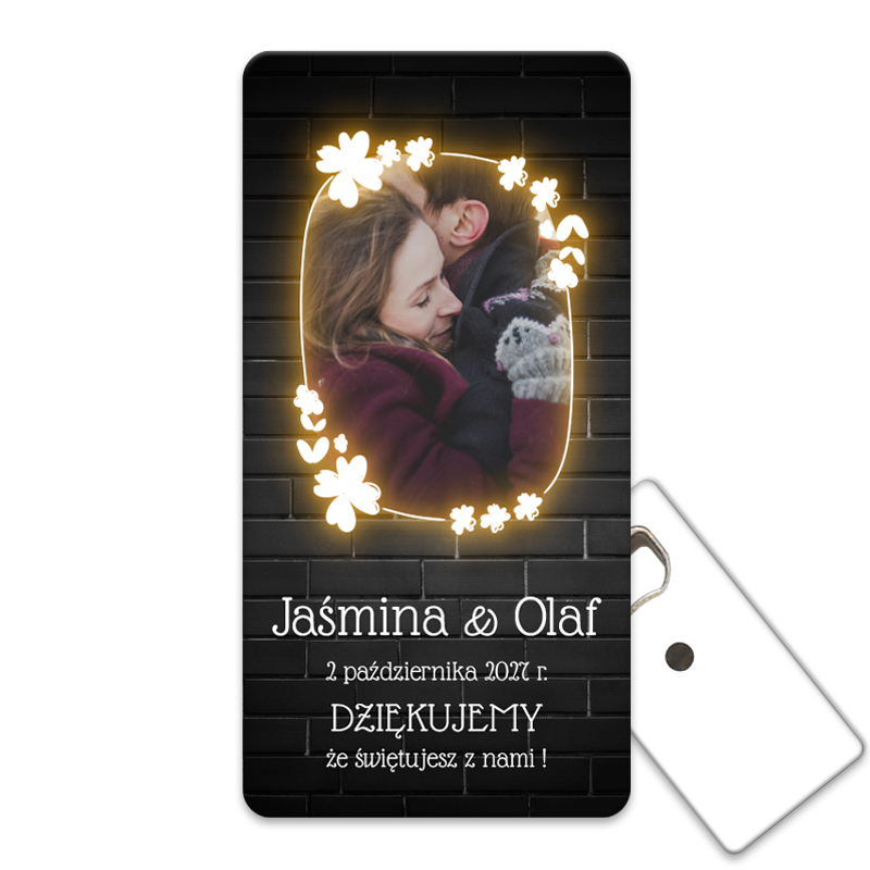 Personalizowany otwieracz do butelek prezenty dla gości weselnych z neonową ramką na zdjęcia z kwiatowym wzorem na tle czarnej cegły.